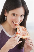 Portrait of woman eating pizza slice. Photographe : Daniel Grill