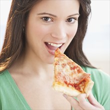Portrait of woman eating pizza slice. Photographe : Daniel Grill