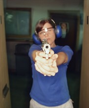 Young woman holding gun. Photographe : Stewart Cohen