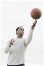 Man playing with basketball, studio shot. Photographe : PT Images