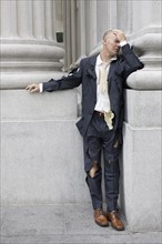 Businessman wearing torn clothing outside office building, San Francisco, California, USA.