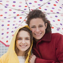 Mother and daughter (10-12 years) under umbrella, portrait. Photographe : Jamie Grill