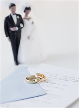 Wedding rings by bride and groom cake toppers on marriage certificate. Photographe : Jamie Grill