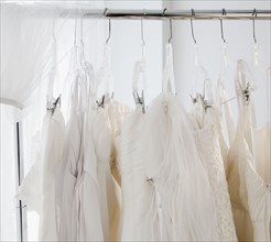 Row of wedding dresses hanging on clothes rail. Photographe : Jamie Grill