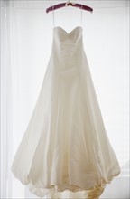 Wedding dress on hanger, studio shot. Photographe : Jamie Grill