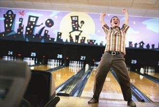 Man standing in front of bowling alley and cheering. Photographe : Stewart Cohen