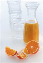 Fresh orange juice in decanter with oranges slices, studio shot.