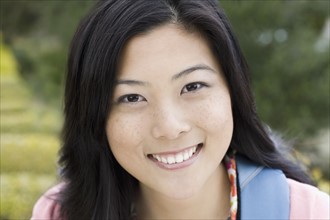 Portrait of young woman smiling, outdoors. Photographe : PT Images