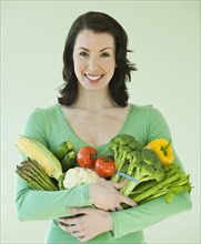 Woman holding various vegetables.