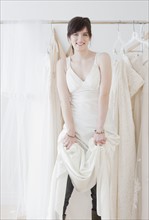 Portrait of young woman wearing wedding dress in shop. Photographe : Jamie Grill