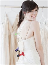 Portrait of young woman wearing wedding dress in shop. Photographe : Jamie Grill