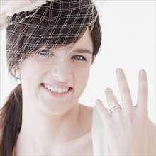 Portrait of bride wearing wedding dress, showing ring. Photographe : Jamie Grill