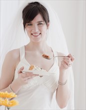 Portrait of bride eating wedding cake. Photographe : Jamie Grill