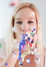 Portrait of young woman blowing confetti. Photographe : Jamie Grill