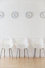Row of chairs in waiting room under clocks displaying time zones.