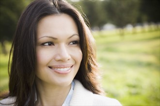 Close-up of woman smiling in park. Photographe : PT Images