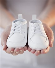Close-up of woman holding baby shoes.