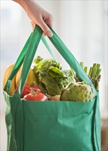 Woman holding grocery bag, close-up.