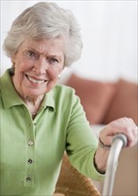 Senior woman sitting and holding walking stick.