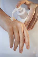 Close-up of woman using hand moisturizer.