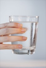 Close-up of woman's hand holding glass of water.