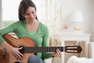 Mid-adult woman playing guitar.