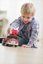 Boy (3-4) playing with toy fire engine.