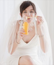 Portrait of bride blowing bubbles. Photographe : Jamie Grill