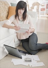 Young woman paying bills via Internet. Photographe : Jamie Grill