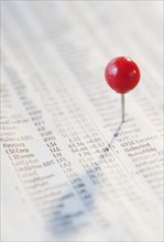 Close-up of pin on stock market newspaper. Photographe : Jamie Grill