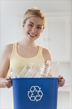 Portrait of young woman holding recycling bin. Photographe : Daniel Grill