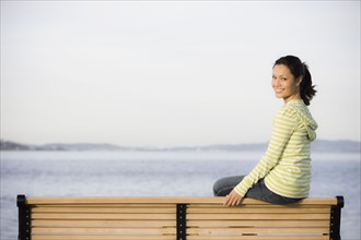 Portrait of woman relaxing on bench near sea. Photographe : PT Images