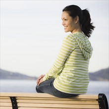 Woman relaxing on bench near sea. Photographe : PT Images
