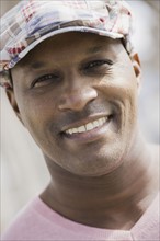 Portrait of man wearing cap, smiling. Photographe : PT Images