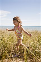 Beaver Island, Girl running in grass on beach, Beaver Island, Michigan, USA. Photographe : Shawn