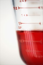 Measuring jug filled with red liquid, close-up. Photographe : Joe Clark