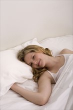 Young woman laying in bed. Photographe : David Engelhardt