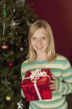 Teenage girl (13-15) holding Christmas present, portrait. Photographe : Sarah M. Golonka