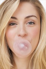 Studio portrait of young woman blowing bubble. Photographe : Daniel Grill