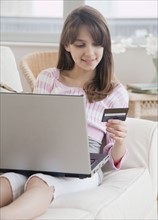 Preteen girl (10-12 years) doing online shopping and holding credit card. Photographe : Jamie Grill