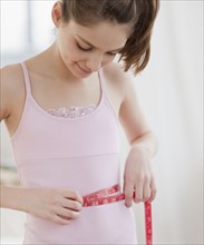 Preteen girl (10-12 years) measuring waist. Photographe : Jamie Grill
