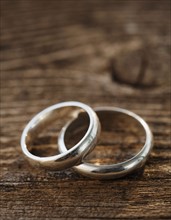 Two wedding rings on wooden table. Photographe : Jamie Grill