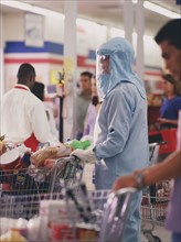 Woman in protective workwear in supermarket. Photographe : Stewart Cohen