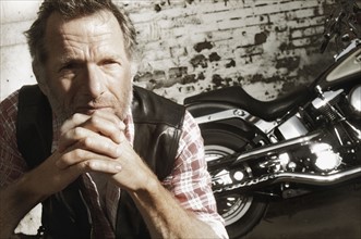 Mature man in front of motorcycle. Photographe : Stewart Cohen