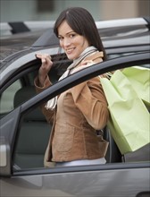 Portrait of woman getting into car with shopping bags.