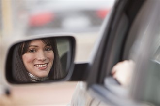 Reflection of woman in side view mirror.