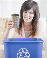 Portrait of young woman putting can in recycling bin. Photographe : Jamie Grill