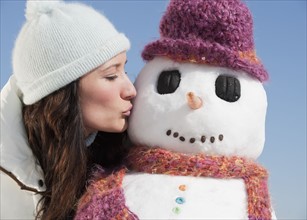 Woman kissing snowman.
