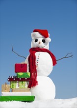 Snowman and Christmas presents, clear sky in background.