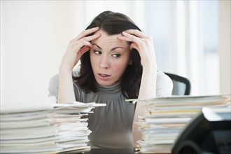Stressed business woman observing paperwork in office.